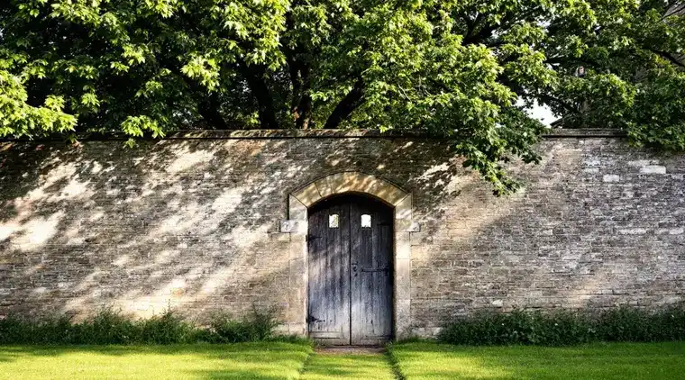 Tree surgeon in Wetherby Mature tree behind an old stone garden wall with an arched door, typical of Wetherby, LS22